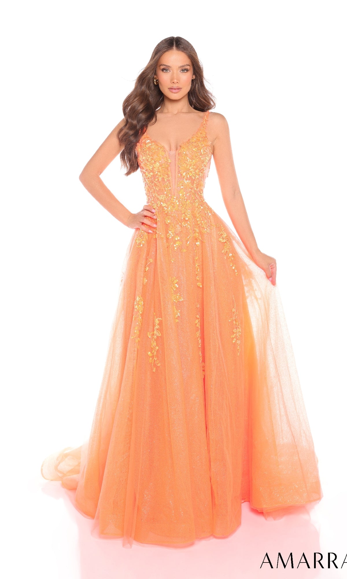 A woman poses against a white background in the Amarra 88341 long A-line glitter prom dress, featuring orange sequins, floral embellishments, a sleeveless design, and a fitted bodice.